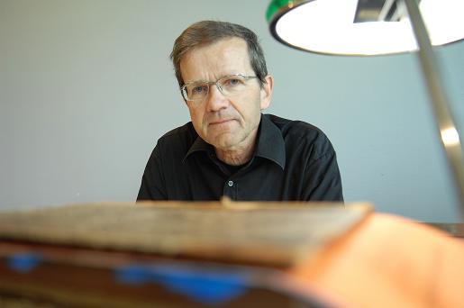 En mann med briller sitter ved en pult på en lesesal