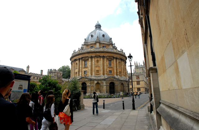 Ein gammal universitetsbygning i Oxford med studentar i gata.
