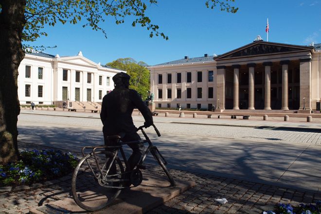 Skulptur av ein person på sykkel framfor Universitetets aula på Karl Johan