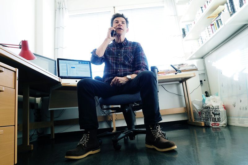 Ein mann sit og snakkar i mobiltelefonen på kontoret sitt
