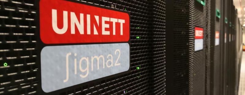 Skilt med Uninett Sigma 2 festa på veggen til eit rom med ei superdatamaskin