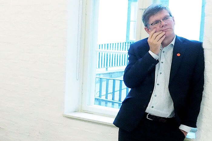 En stående mann støtter seg mot veggen