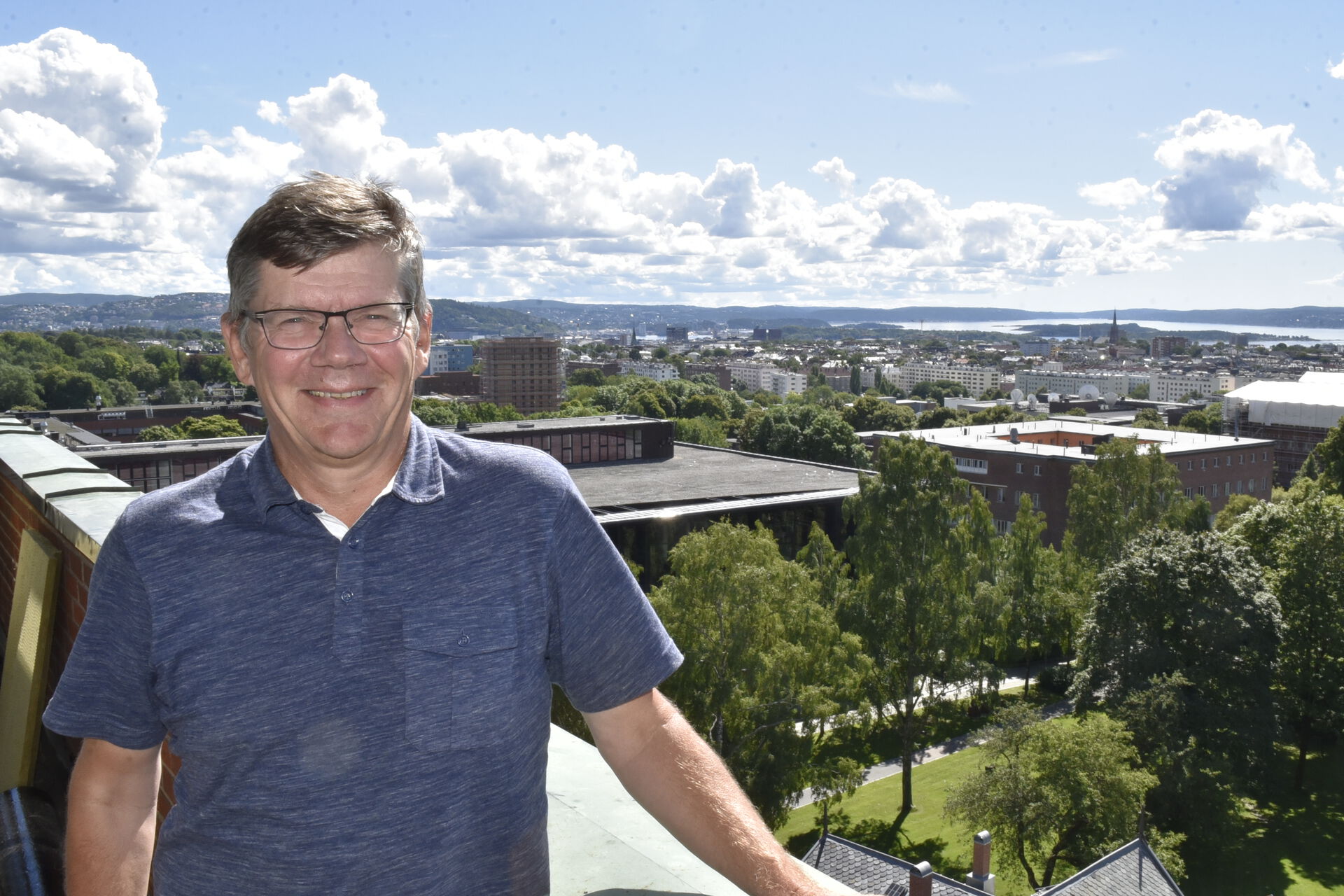 Ein mann står på ein terrasse og har utsyn over Oslo bak seg