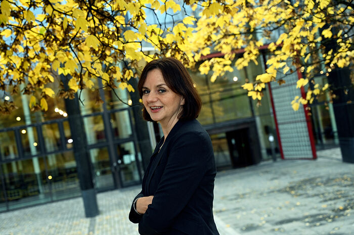 Ei kvinne står framfor ein svær bygning i svart marmor
