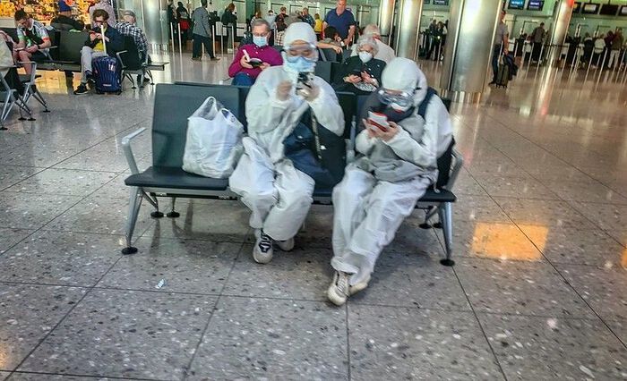 Personer med verneutstyr venter i en avgangshall på en flyplass