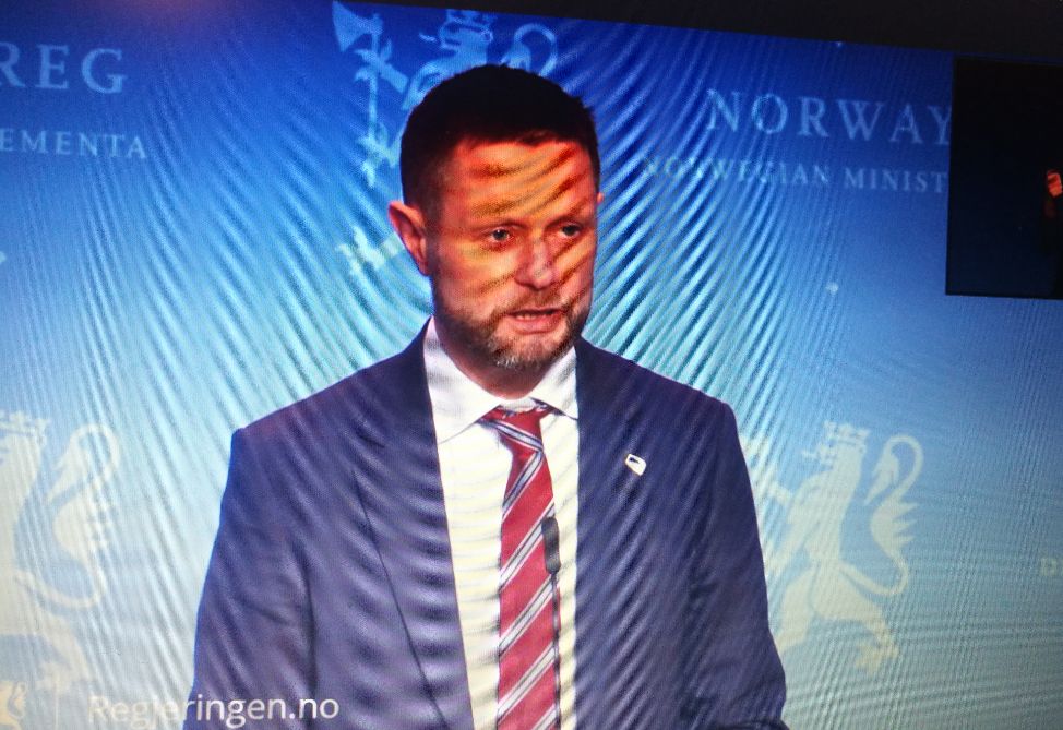 En mann med slips står foran en mikrofon