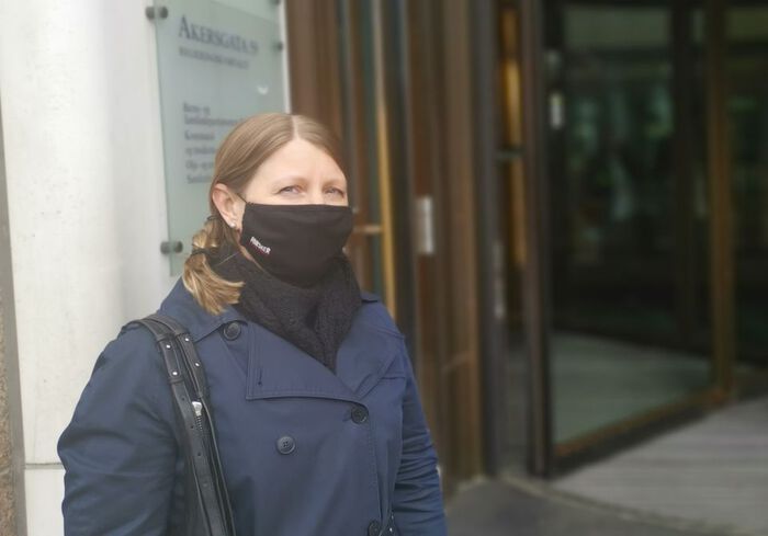 En kvinne med munnbind står utenfor en hovedinngang