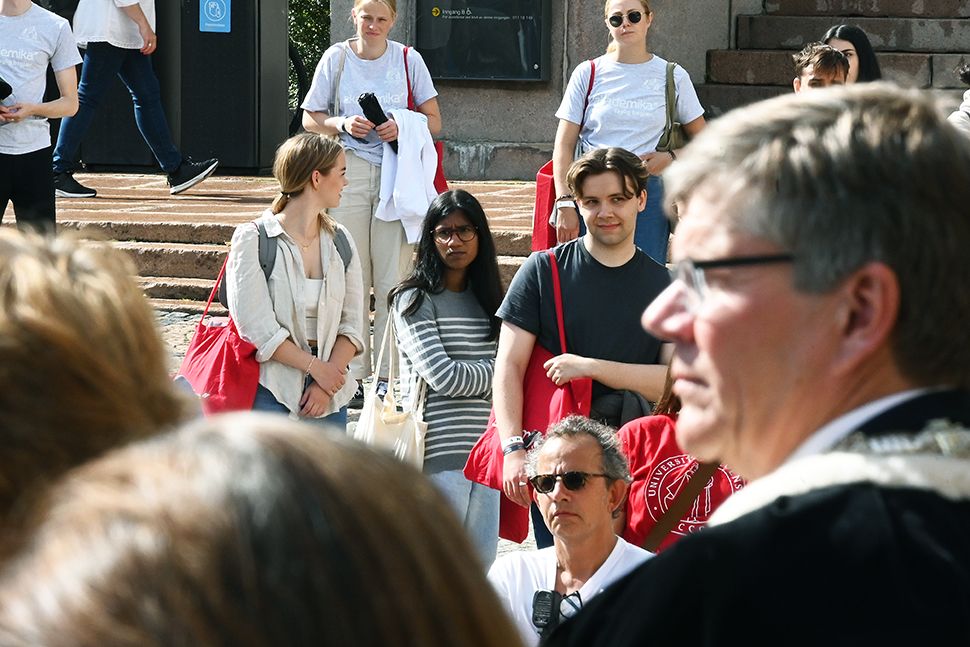 En mann med kappe ser studenter på Universitetsplassen