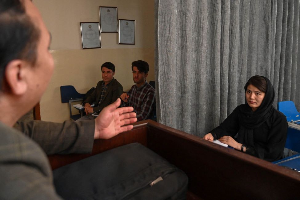 Tre menn og en kvinne under en forelesning i Kabul