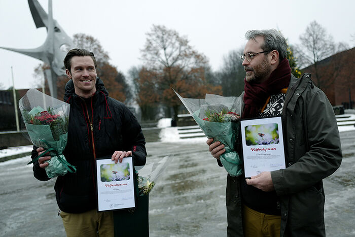 To menn står midt på Frederikkeplassen med to premier