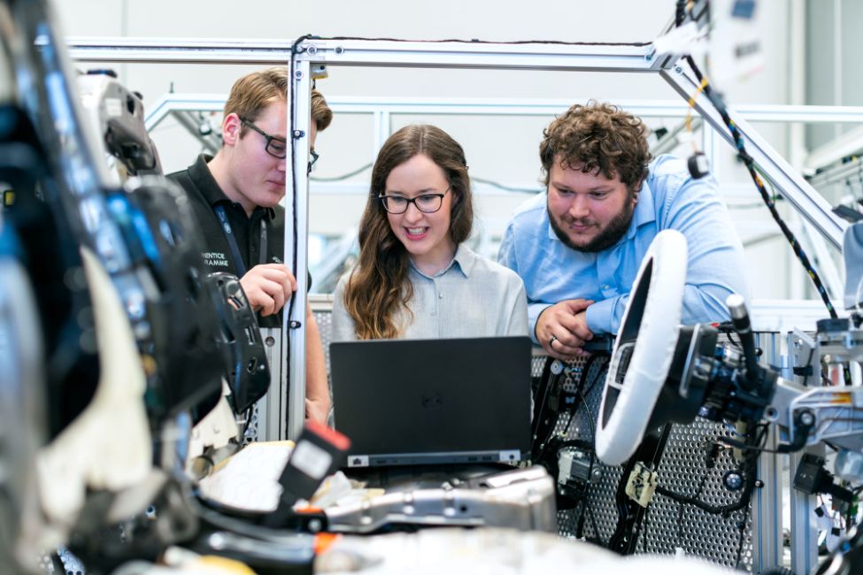 Tre forskere står foran en bærbar datamaskin