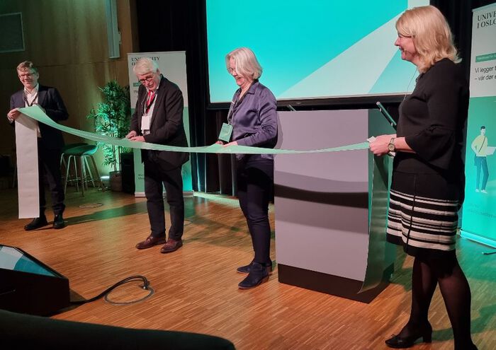 To menn og to kvinner klipper over ei snor