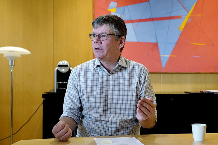 Portrett av en mann med briller foran et skrivebord