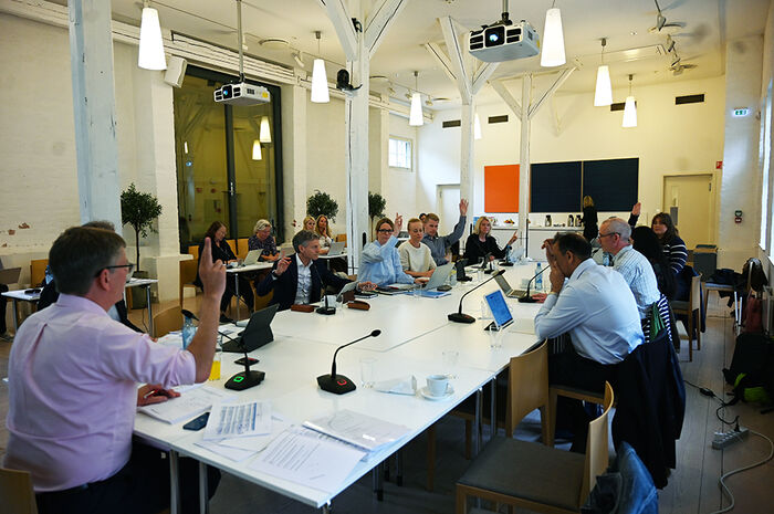 Fleire personar er samla rundt eit styrebord