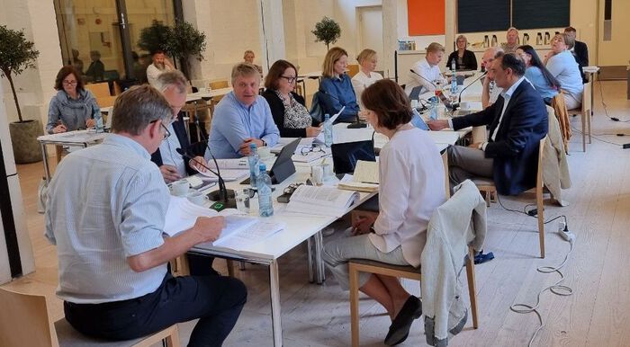 Mange folk er samla rundt eit møtebord