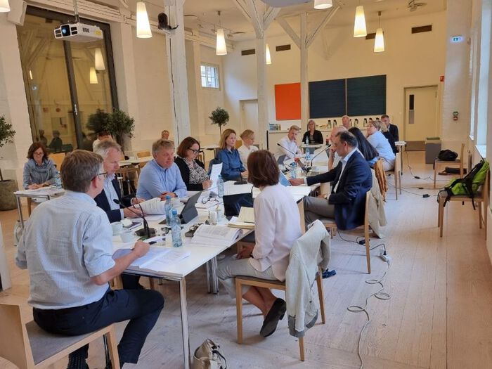 Mange personar er samla rundt eit møtebord i Professorboligen