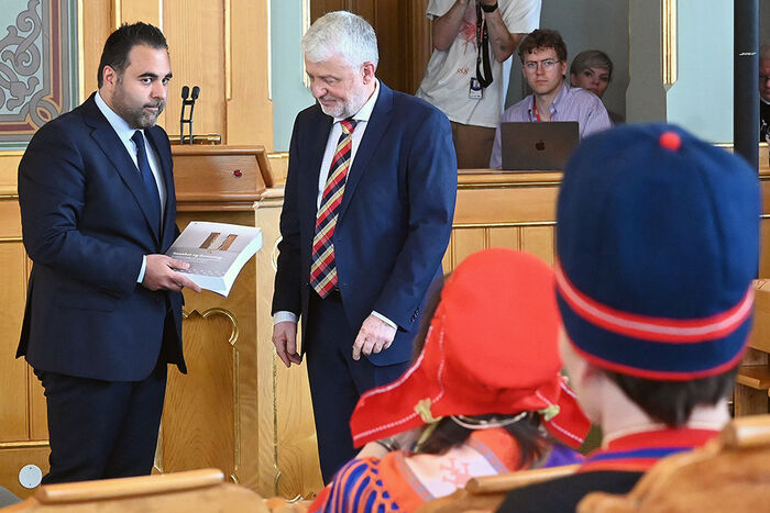 To menn står framfor ein talarstol i Stortinget