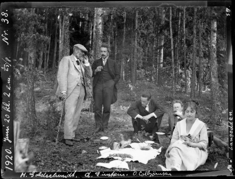 Bildet viser Albert  Einstein stående i samtale med kjemiprofessor Heinrich Goldsmith, mens tre andre personer sitter, blant andre Einsteins adoptivdatter Ilse. De er på tur til Langodden i Oslofjorden